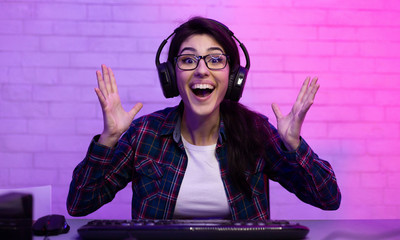Female Gamer Celebrating Winning Computer Game Shaking Hands Sitting Indoor