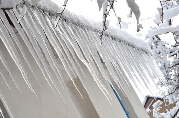  Icicles hanging from the roof of the house.