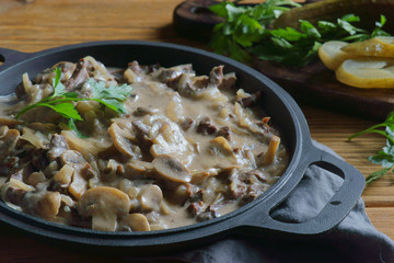 beef Stroganoff in a frying pan on a wooden background