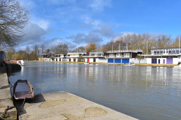 Boats and rowing clubs on the Thames in Oxfordshire Pleasant walk down the river banks on sunny day in south east England Heavy rain caused the water level to go up even flood the British countryside
