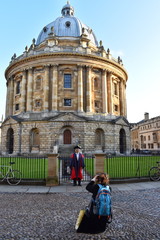 Student in academic outfit posing in from of a library in Oxford Graduates obtain gown cap and...