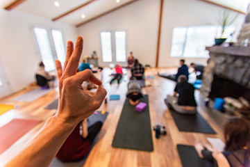 The man showing an OK gesture to a people taking a part yoga class. A hand of a man showing OK....