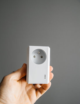 Man hand holding against gray background a new modern powerful powerline Ethernet internet adapter