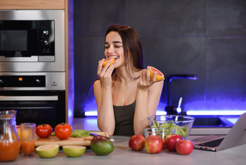 Young beautiful girl eating an orange, in bright clothes on an white background.