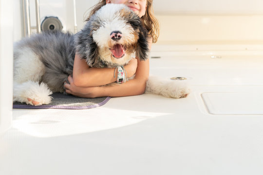 Young girl holding onto a puppy on a boat