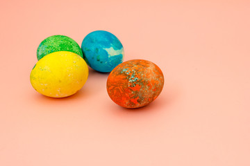 Four multi-colored Easter eggs on pink background top view, space for text. Concept happy easter day.
