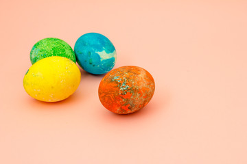 Four multi-colored Easter eggs on pink background top view, space for text. Concept happy easter day.