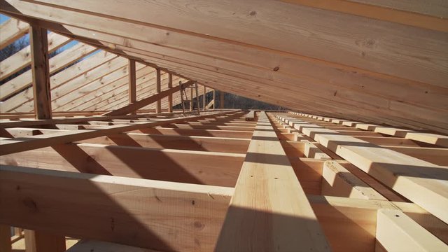 Camera is moving backward, view of the area under wooden roof beams, future attic of the frame house under construction