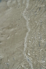 gentle wave of water meets the sandy beach  