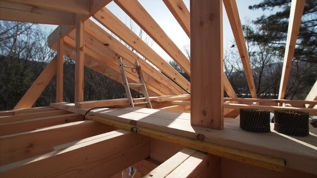 Panoramic view of Interior of future attic in the frame house under construction, safe harnessing left by builders. Bright sun is shining through the roof beams