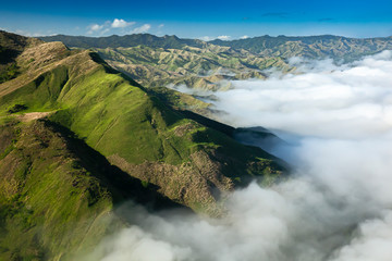 fiji aerial of green mountains with deep valleys and thick white fog on a sunny day. Yasawa island...