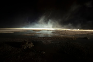 abstract mars like terrain with muddy puddles of water textures, rocks and heavy fog rolling...