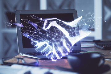 Desktop computer background in office and handshake hologram drawing. Double exposure. Pertnership...