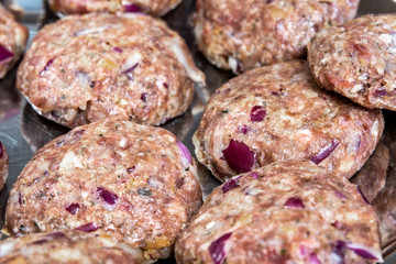 raw ground beef (minced meat), meatballs containing onions and other ingredients on a plate 