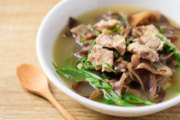 Spicy brown jelly mushroom soup with pork in a bowl on wooden table, Local Thai food