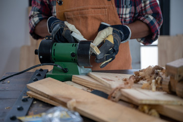 Carpenter working on woodworking machines in carpentry shop, wooden product