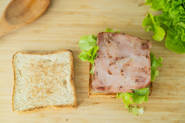 Tasty and fresh sandwiches in kitchen room. Man prepares lunch, serves grilled bread sandwich snack on top of wooden cutting board.