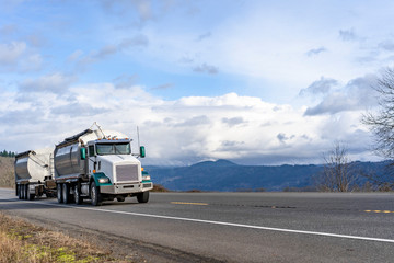 Big rig tip truck with two dump trailers running on the road with mountain and cloud sky view in Columbia Gorge
