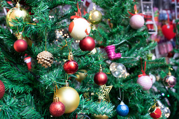 Obraz na płótnie Canvas Decorative Christmas decorations close-up. Hanging ornaments on the fake pine tree. There are colored balls on it.