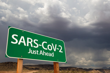 SARS-CoV-2 Coronavirus Green Road Sign Against Ominous Stormy Cloudy Sky