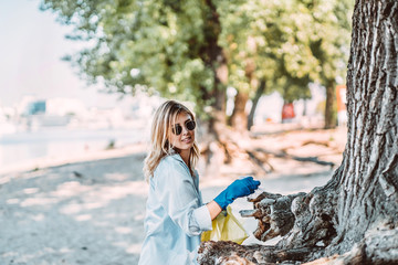 Girl picking up trash from the park. She collecting the litter in garbage bag