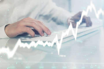 Double exposure of graph with man typing on computer in office on background. Concept of hard work....