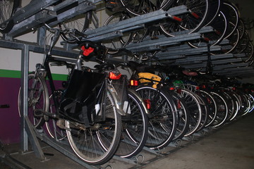 A bike stand in the netherlands, a very large amount of biked bicycles from which the reflectors of the wheels light up