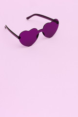 Stylish heart shaped glasses on pink background with copy space. Beautiful trendy purple...