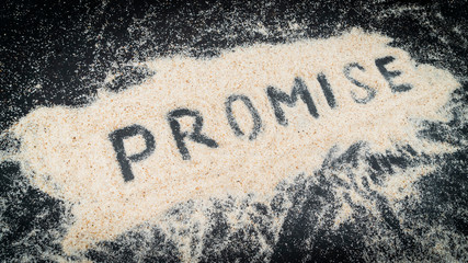 Closeup of PROMISE text written on white sand