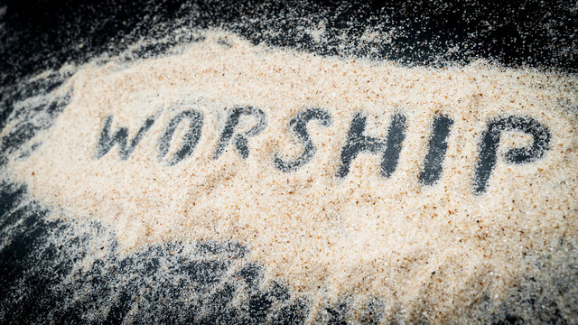 Closeup of WORSHIP text written on white sand