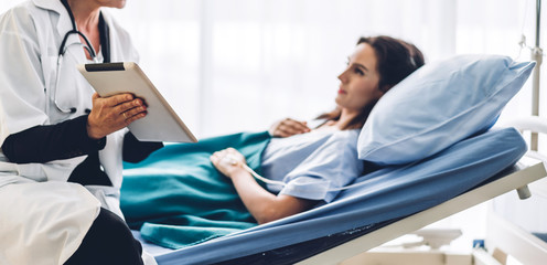 Obraz premium Doctor discussing and consulting check up information on tablet computer with female patien on the bed in hospital.healthcare and medicine