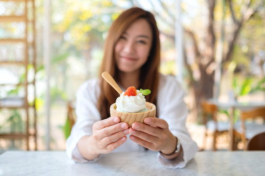 Closeup image of a beautiful asian woman showing and eating an ice cream in restaurant