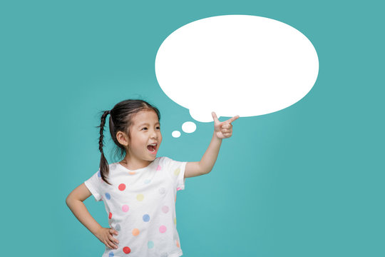 Beautiful smiling Asian little girl pointing hand to blank speech bubble, empty space in studio shot isolated on colorful blue background, Educational concept for school