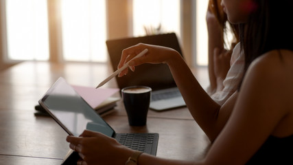 Side view of college girl concentrating on her assignment with digital tablet and stylus