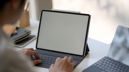 Cropped shot of male entrepreneur typing on laptop on white table