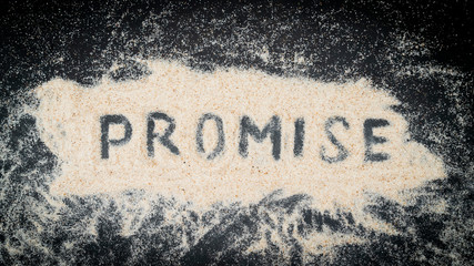 Flat lay of PROMISE word written on white sand