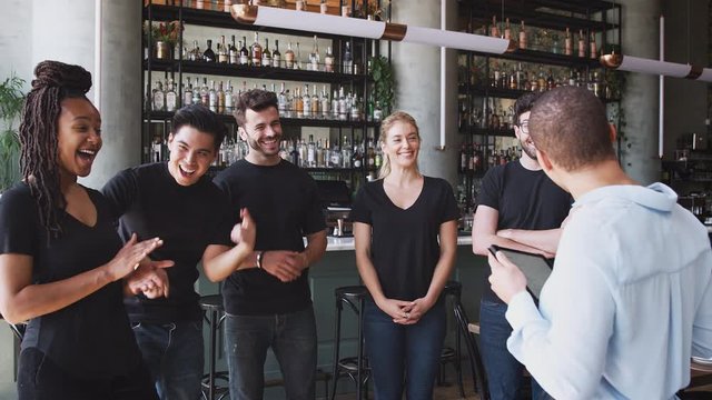 Female restaurant bar manager holding digital tablet giving motivational talk to waiting staff before opening - shot in slow motion