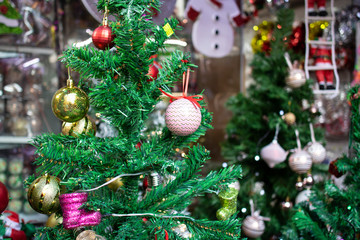 Decorative Christmas decorations close-up. Hanging ornaments on the fake pine tree. There are colored balls on it.