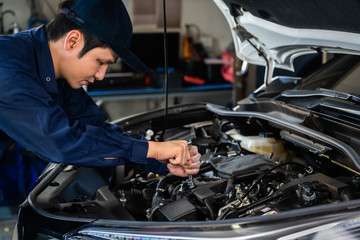 Fototapeta na wymiar male mechanic using wrench to repair engine, car service