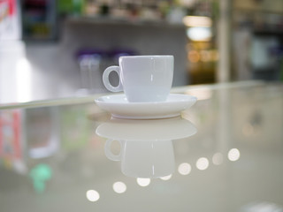 White little cup of espresso coffee on a table in a cafe. Defocused room