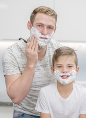 Young man and his son shave in front of a mirror