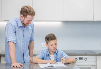 Fototapeta premium Father helps his son doing homework at home. Empty space for text
