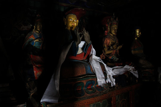 Buddhist statue in the dark room of temple in the monastery. Buddhism in Tibet, religious artifact, picture of God, saint person. Painted cultural object
