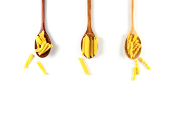 Various types of italian pasta concept. Raw gemelli, penne, casarecce in wooden spoons on white background. Top view, copy space.