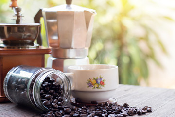 A cup of hot espresso coffee mugs and roasted coffee beans with moka pot placed on wooden floor background,coffee morning,selective focus
