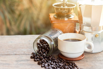 A cup of hot espresso coffee mugs and roasted coffee beans with moka pot placed on wooden floor background,coffee morning,selective focus