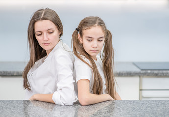 Sad girl and her mother sit at home after they quarreled. Family relationships