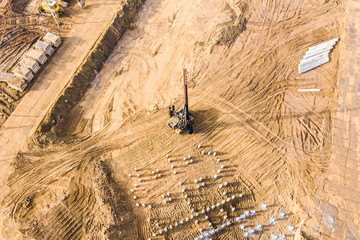 pile driver at work in foundation pit. construction of apartment building. aerial view from flying...
