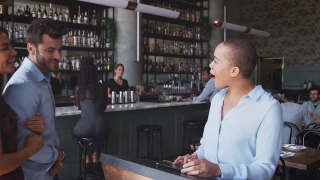 Couple being greeted by maitre d using digital tablet as they arrive at restaurant - shot in slow motion