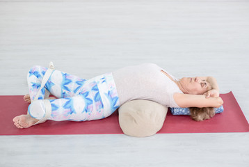 Senior woman practicing yoga, lying in Reclined Butterfly exercise. Sport healthy concept